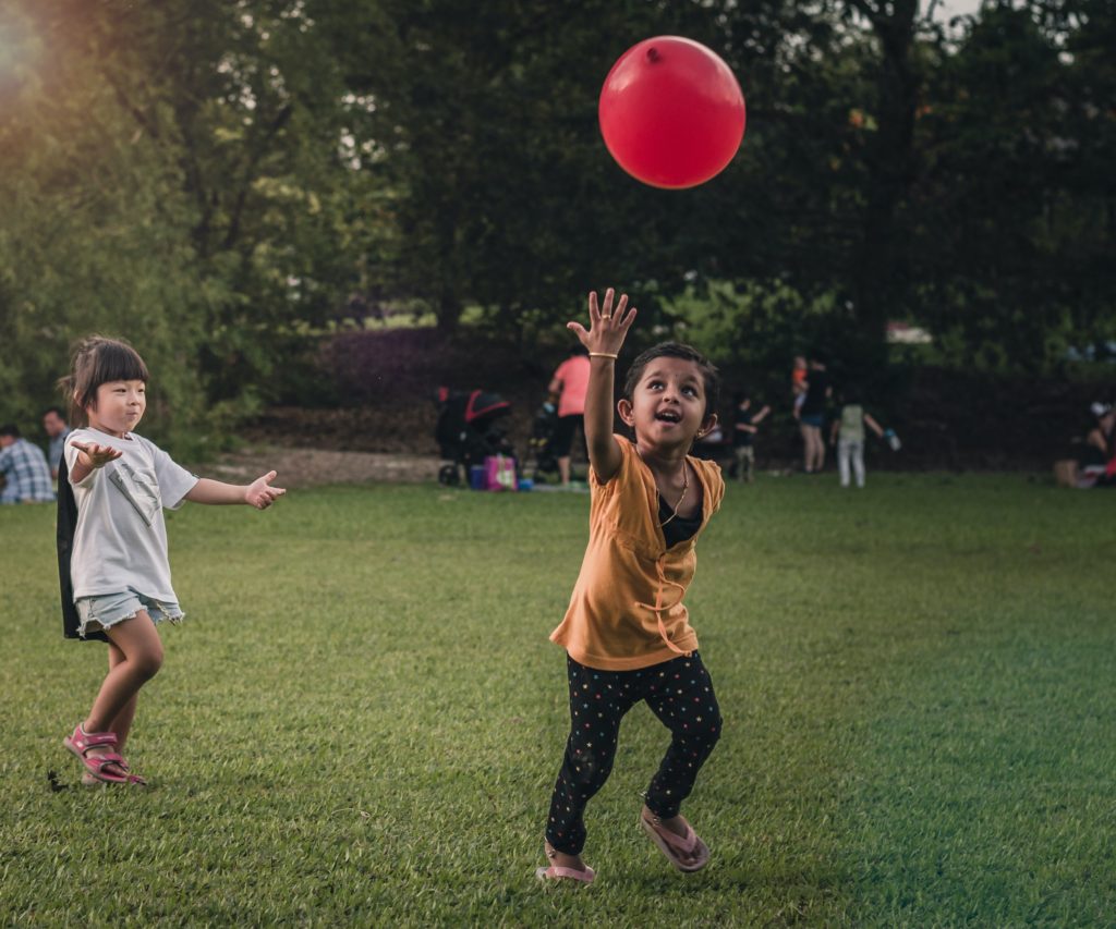 Photo by Alaric Sim on Unsplash - Showit kids playing with balloon in park